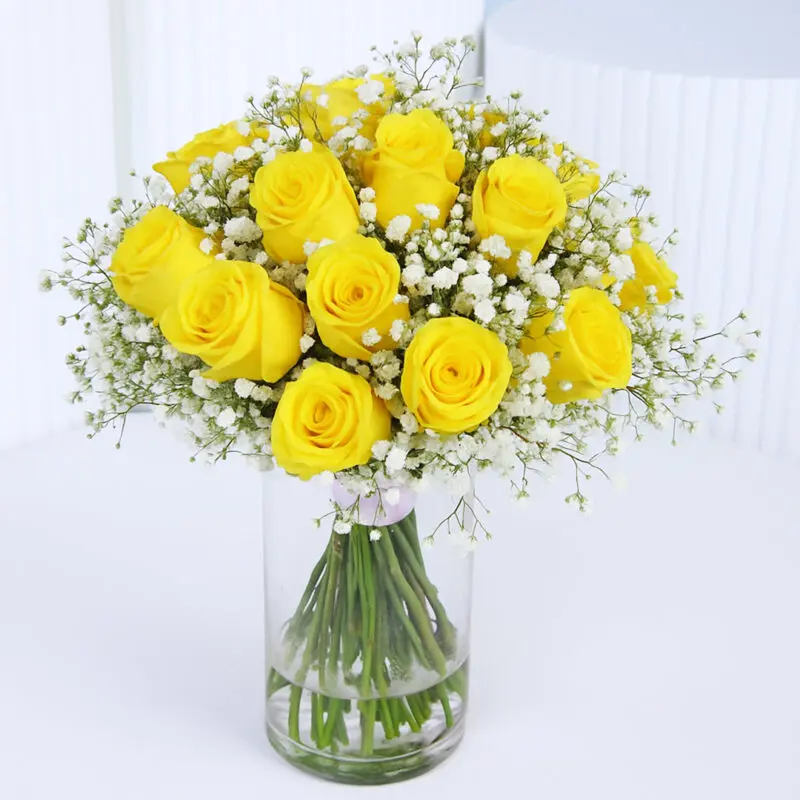 yellow-rose-vase Vibrant yellow roses with white baby's breath arranged in a cylindrical glass vase.