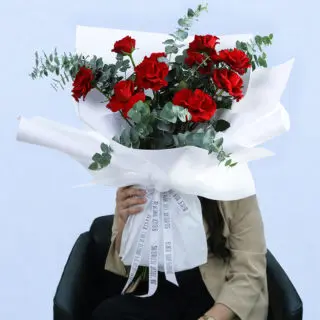 A bouquet of vibrant red roses and eucalyptus, ideal for romantic occasions or expressing care for someone special.
