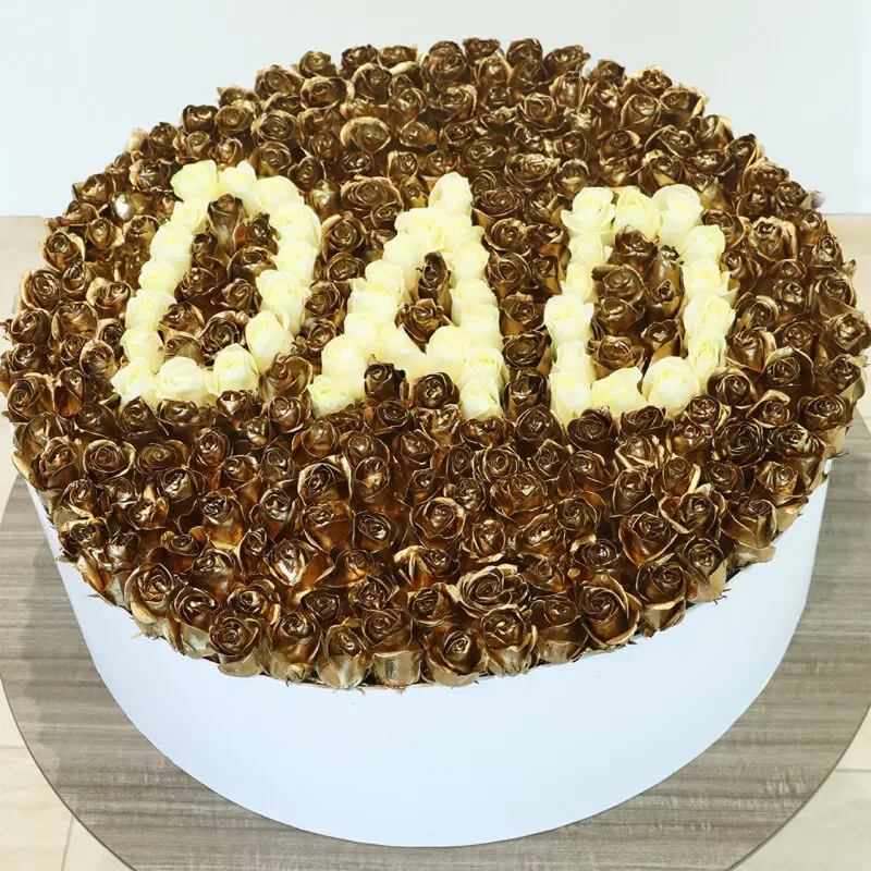 gold-rose-box A large floral arrangement made of gold-coloured roses, with the word "DAD" spelled out in cream-colored roses in the center in a white round box.