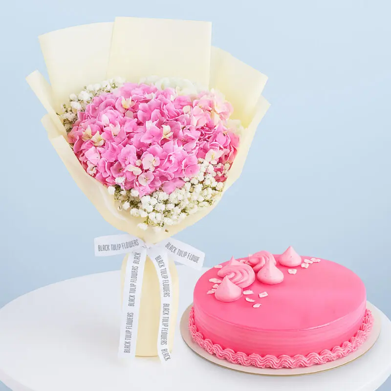 pink-hydrangea-bouquet-cake-01 A flower combo featuring a bouquet of pink hydrangeas with baby's breath wrapped in cream and tied with a black and white ribbon with a round pink frosted cake.