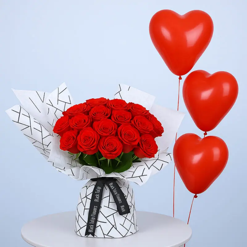 red-rose-bouquet-balloons-01-08-2025 A bouquet of red roses wrapped in black and white geometric patterned paper and tied with a black ribbon and red heart-shaped balloons.