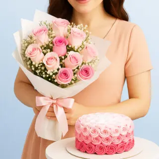 A woman holding a bouquet of light and dark pink roses with baby's breath wrapped in white paper with a pink ribbon and a round cake decorated with pink ombre rosettes.