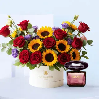 White box arrangement with sunflowers, red roses, purple lisianthus, and eucalyptus, displayed beside a Versace Crystal Noir perfume bottle.