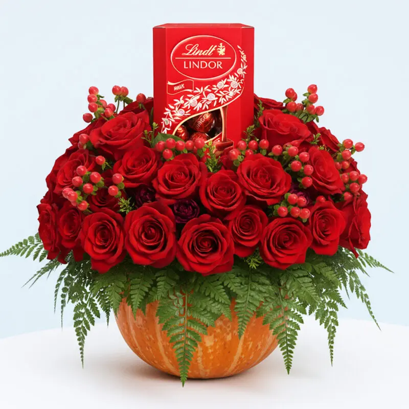 red-rose-pumpkin-with-lindt-chocolates-01-10 Pumpkin flower arrangement with 50 red roses, red hypericum berries, and Lindt chocolates for Halloween floral gift.