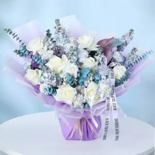 Bouquet with white roses, blue mattiola, carnations, eucalyptus, and a single anthurium wrapped in lilac.