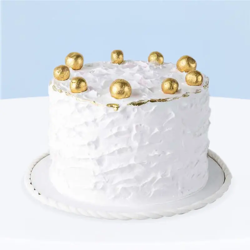 White smudge-textured buttercream cake with gold balls on top, 1 kg.