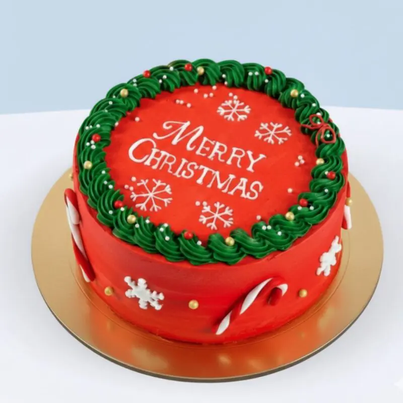 christmas-chocolate-fudge-cake Merry Christmas round chocolate fudge cake with red icing, green cream border, white snowflakes and candy cane decorations on a serving plate.