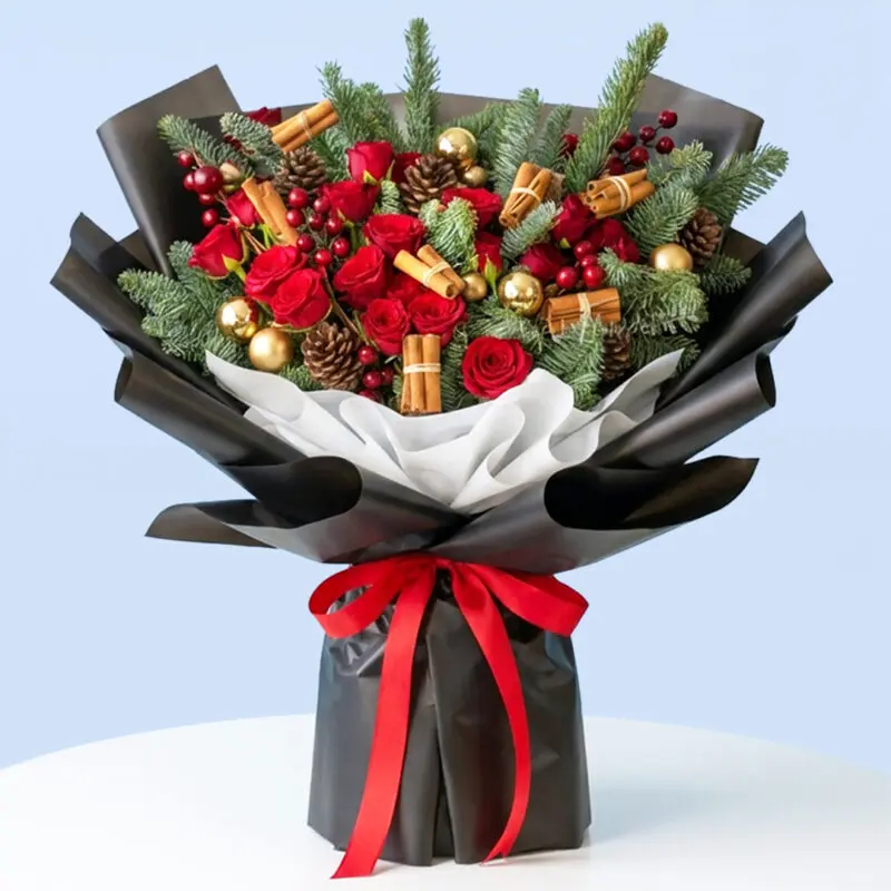 cinnamon-spice-christmas-rose-bouquet Christmas bouquet of red roses, berries, pinecones and cinnamon sticks with foliage, wrapped in black and white and tied with a red satin ribbon.