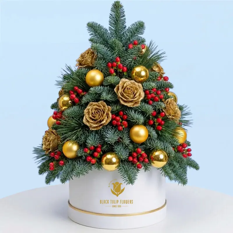golden-rose-berry-christmas-tabletop-tree Tabletop Christmas tree with lush green branches decorated with gold roses, red berries and gold baubles in a white box.