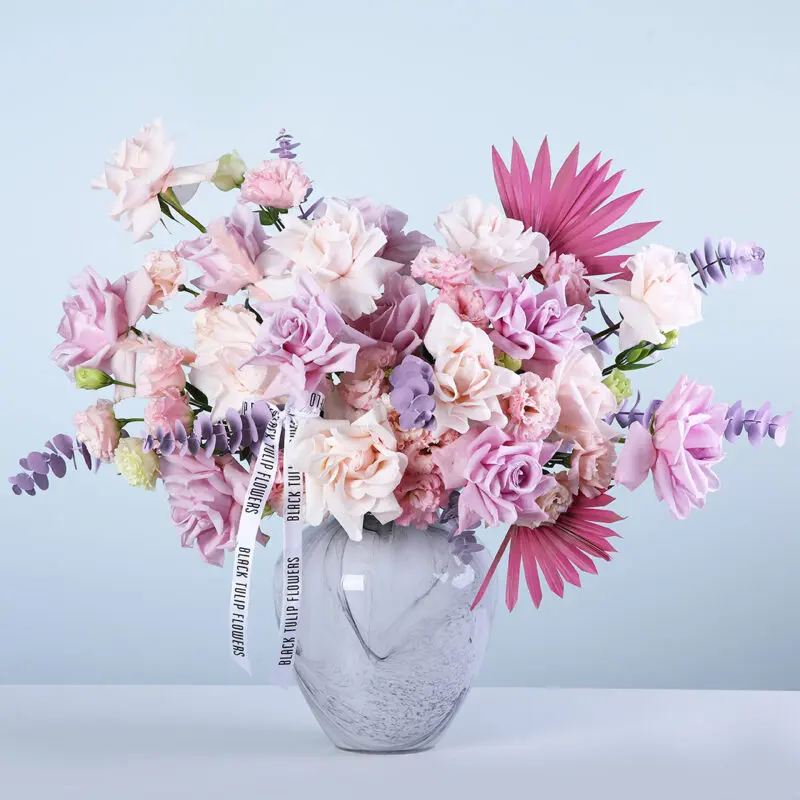 pink-purple-roses-lisianthus-vase Light pink and purple roses with lisianthus and premium fillers in a marble-effect glass vase arrangement, finished with a white ribbon.