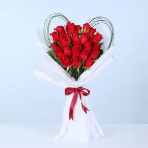 20 red roses arranged in a heart-inspired outline with loop accents in white wrapping, finished with a red ribbon.