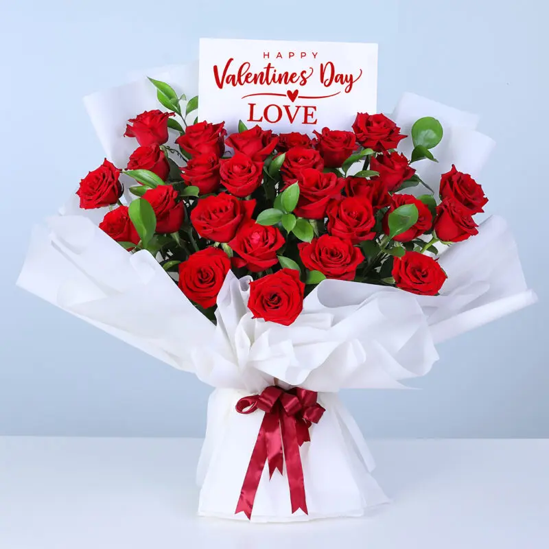 25-red-roses-white-wrap-04-21 Bouquet of 25 red roses and lush greenery in white wrapping, finished with a message card.