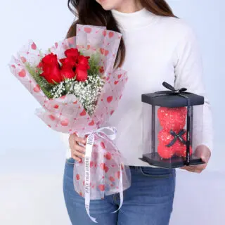 Valentines Day Home 48 Bouquet featuring 7 red roses, gypsophila, and lepidium in heart-print wrapping, paired with a boxed teddy.