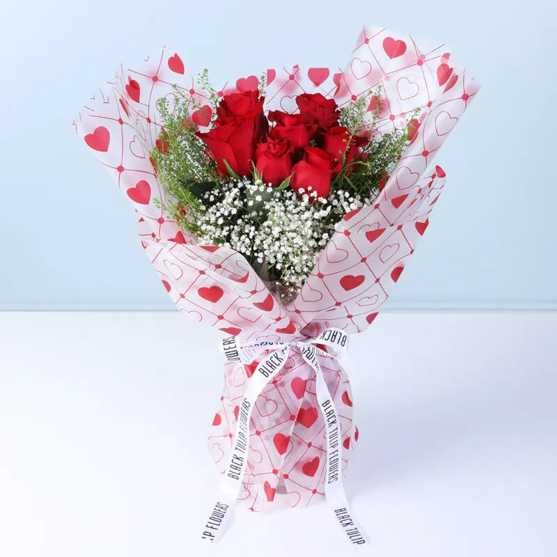 7-red-roses-heart-wrap-bouquet Bouquet of 7 red roses, gypsophila, and lipidium in heart-print wrapping.