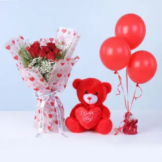 Bouquet featuring 7 red roses, gypsophila, and lipidium in heart-print wrapping, paired with a red teddy and red balloons.