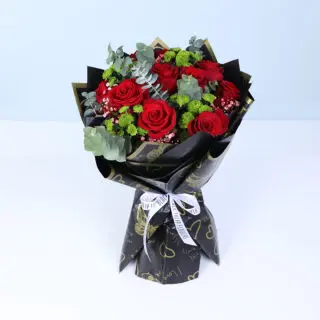 Hand-tied Valentine bouquet with fresh red roses wrapped in premium black paper and tied with a ribbon, designed for modern romantic gifting.