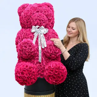 Pink spray roses in a teddy arrangement style, finished with a white ribbon.