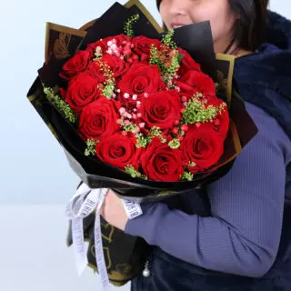 A luxury black-and-gold wrap bouquet featuring red roses, pink baby’s breath and green fillers.