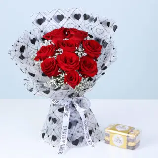 A bouquet featuring red roses and baby’s breath in a heart-patterned white wrap, with a Ferrero chocolate gift box.