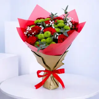Bouquet of red roses, green chrysanthemums, baby’s breath and eucalyptus in bold red wrapping.