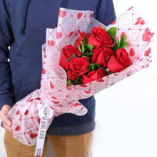 Red roses bouquet with heart-print wrapping tied finished with a white ribbon.