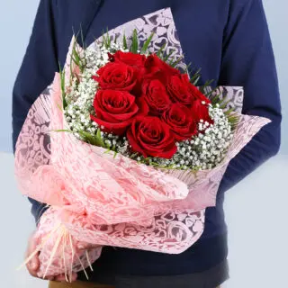 Valentine’s Day red roses bouquet wrapped in soft pink with baby’s breath and greenery.