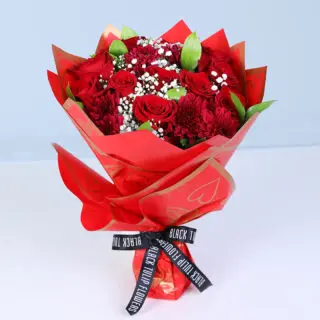 A premium red wrap bouquet featuring red roses, baby's breath, red chrysanthemum blooms, and green leaves finished with a black ribbon.