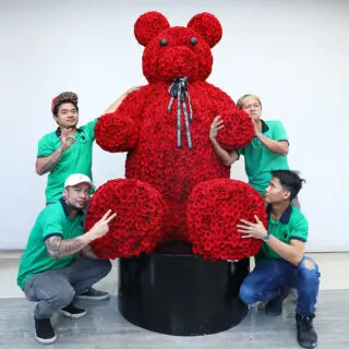 Premium red roses shaped into a royal giant teddy arrangement in a tall luxury box with ribbon finish.