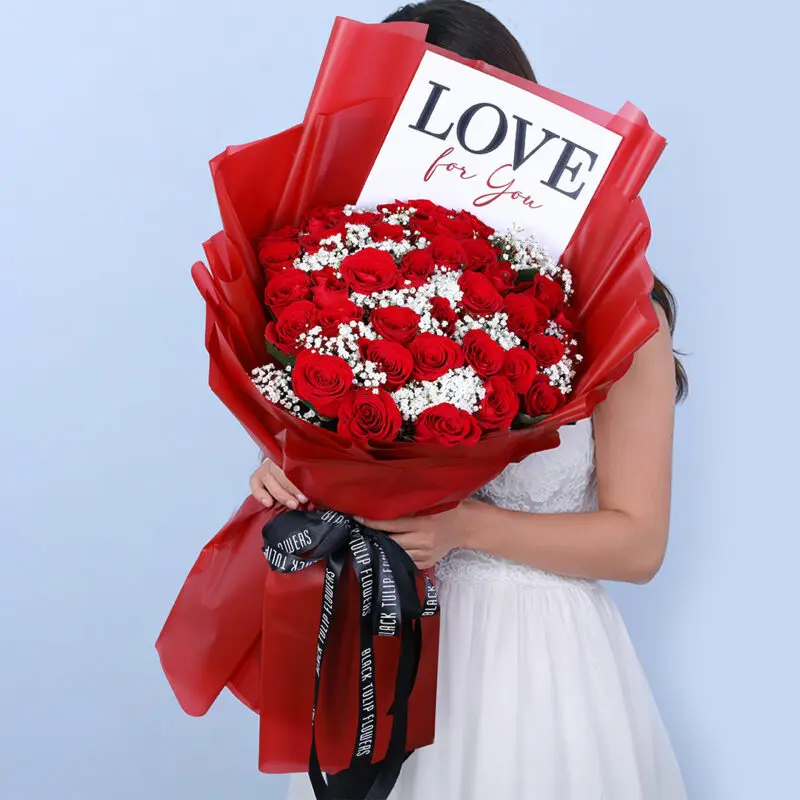 valentine-25-red-roses-gypso-bouquet Hand-tied Valentine bouquet featuring 25 fresh red roses and 5 white gypso fillers wrapped in a red sheet and secured with a black ribbon