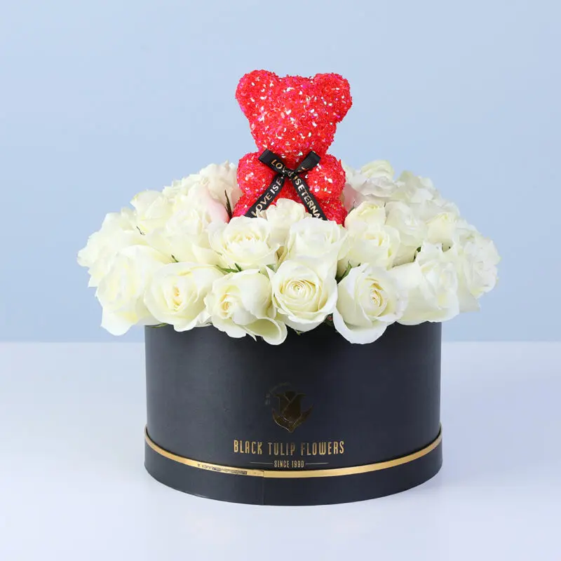white-rose-flower-box-red-teddy White roses arranged in a black box, finished with a red teddy bear.