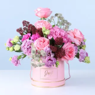 Pink roses, hydrangeas, carnations, and seasonal blooms in a round pink box with gold detailing, finished with a premium presentation.