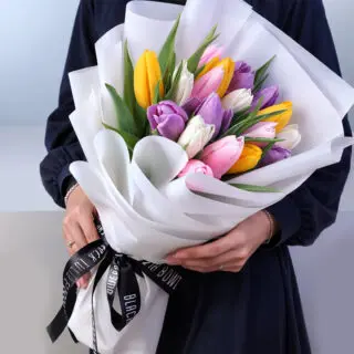 Bouquet featuring 20 mixed tulips in white wrapping style, finished with a black ribbon and a premium presentation.