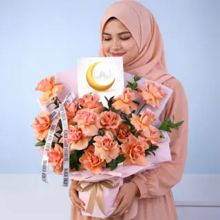 Bouquet featuring 20 fresh orange roses with single ruscus in elegant soft pink wrapping, beautifully finished with a heartfelt “Eid Mubarak” card message, sending warm wishes of joy, peace, and prosperity.