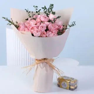 Blush pink spray roses with greenery in nude wrapping, finished with ribbon and paired with a 16-piece Ferrero Rocher chocolate pack.