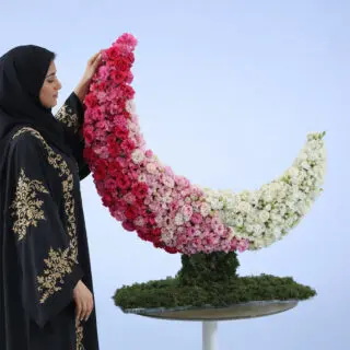 Crescent-shaped floral arrangement featuring pink, red, and white roses on a moss base, luxury Ramadan flower display.