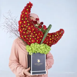 Red chrysanthemums and red roses in a crescent design with green hydrangea in a luxury black box.