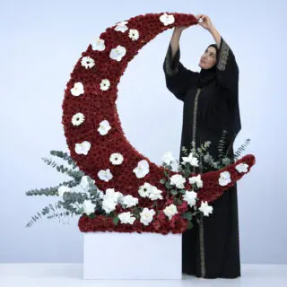 Red chrysanthemums in a crescent design with white orchids and white roses in a rectangular base arrangement