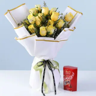 Fresh yellow roses with greenery in premium white gold-edged wrapping, finished with a ribbon bow and paired with a Lindt chocolate box.