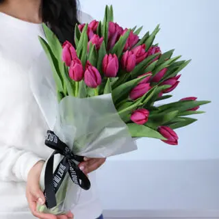 Bouquet of 30 fresh purple tulip flowers wrapped beautifully with green foliage, showcasing vibrant petals and elegant stems arranged as a stylish floral gift.