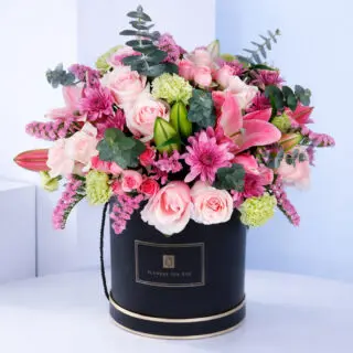 A vibrant assortment of flowers is beautifully displayed in a stylish premium round floral box.