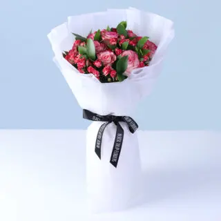 Hand-arranged bouquet of pink roses and small spray roses with natural greenery, creating a soft, romantic, and visually pleasing floral arrangement.