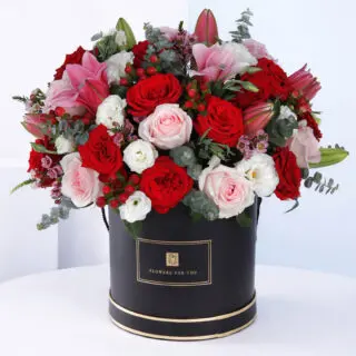 A lush mix of vibrant flowers arranged in a decorative black flower box, designed as a stylish floral gift arrangement.