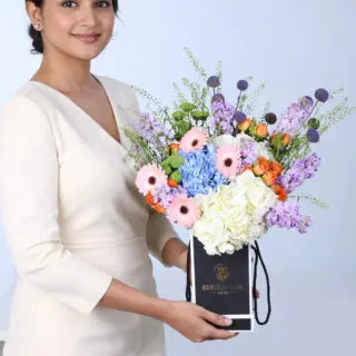 Multi-coloured floral display with Gerbera, Hydrangea, Mattiolla, Caspedia, and Baby Roses arranged in a stylish black box.