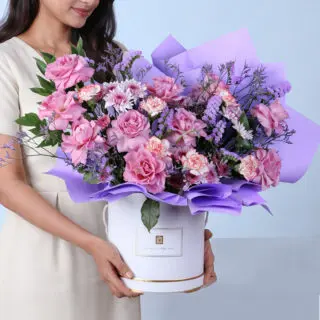 Colorful bouquet of purple roses paired with double color carnations, chrysanthemum lollipops, and soft purple filler flowers for a textured floral display.