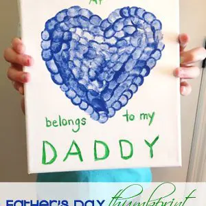 a piece of artwork created for Father's Day. The artwork is on a white canvas and features a heart shape made from blue thumbprints.