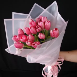 A bouquet of pink tulips wrapped in pink tissue paper