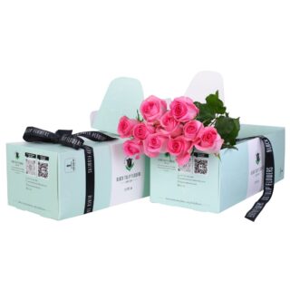 Bunch of pink roses in a green box tied with a black ribbon with flower food.