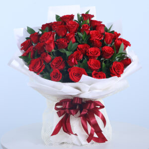 Beautifully wrapped bouquet of 30 red roses and green leaves, tied with a maroon ribbon.