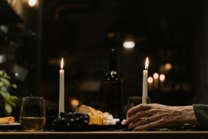 A person's hand reaching for a glass of wine at a dimly lit table.