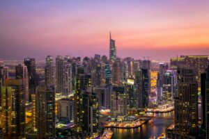 Dubai skyline at sunset, showcasing modern architecture and urbanization against a vibrant, colorful sky.